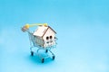 Wooden small decorative house and a key to the lock in a shopping trolley Royalty Free Stock Photo