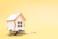 wooden small decorative house stands on a pile of coins Royalty Free Stock Photo