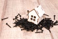 a wooden small house with a window stands on a pile of black screws, a house on nails Royalty Free Stock Photo