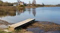 Wooden small rural bridge on cold autumn lake near european vil Royalty Free Stock Photo