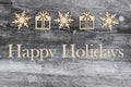 Wooden snowflake and Christmas presents on a weathered wood with text Happy Holidays