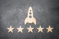 A wooden space rocket and five stars on a concrete background.