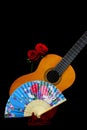 Traditional spanish guitar with a pair of valentine red roses and a paper fan against black background Royalty Free Stock Photo