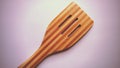 Wooden spatula for gentle cleaning of food that has dried up on dishes or burned to a pan. New wood tool with slots and dark