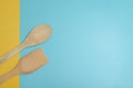 Two wooden spatulas on cyan surface.