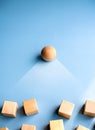 Wooden sphere stand alone at the leader position of group of wood cube blocks on blue background, vertical style. Leadership,.