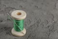 wooden spool with green thread and sharp needle