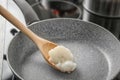 Wooden spoon with coconut oil in frying pan Royalty Free Stock Photo