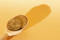 Wooden spoon with coins on a beige background. Royalty Free Stock Photo