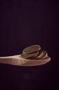 Wooden spoon with Colombia currency coins against dark background, vertical shot Royalty Free Stock Photo