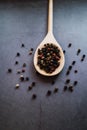 Wooden spoon for cooking with pepper on concrete background. Seasoning condiment. Close up view Royalty Free Stock Photo