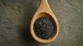 Wooden spoon filled with black sesame seeds on textured surface Royalty Free Stock Photo