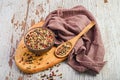 Wooden spoon filled with fresh peppercorns atop a tray on a white table