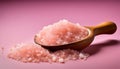 A wooden spoon is filled with pink salt