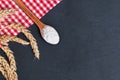 Wooden spoon with flour, wheat ears and red checkered cloth on black table Royalty Free Stock Photo