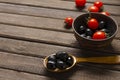 Wooden spoon full of black olives, bowl, fresh tomatoes onthe rustic surface.Empty space Royalty Free Stock Photo