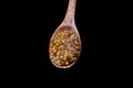 Wooden spoon full of french mustard isolated on black background. Royalty Free Stock Photo