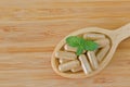 Wooden spoon full of herbal medicine in clear capsules, ideal for Homeopathic remedies Royalty Free Stock Photo