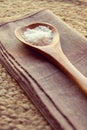 Wooden spoon full of sea salt flakes on rustic background Royalty Free Stock Photo