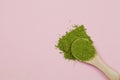 Wooden spoon with green matcha tea powder on pink background Royalty Free Stock Photo