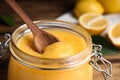 Wooden spoon in jar with lemon curd on table, closeup