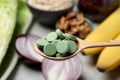 Wooden spoon of pills over table with foodstuff, closeup. Prebiotic supplements Royalty Free Stock Photo