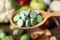 Wooden spoon of pills over table with foodstuff, closeup. Prebiotic supplements Royalty Free Stock Photo