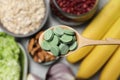 Wooden spoon of pills over table with foodstuff, top view. Prebiotic supplements Royalty Free Stock Photo