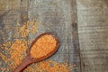 Wooden spoon with pink lentil on rustic wooden board