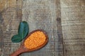 Wooden spoon with pink lentil on rustic wooden board