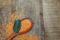 Wooden spoon with pink lentil on rustic wooden board