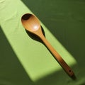 A wooden spoon is placed on a green fabric surface, illuminated by sunlight. The spoo Royalty Free Stock Photo