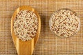 Wooden spoon with quinoa, bowl with quinoa seeds on mat. Top view