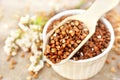 Wooden spoon of roasted buckwheat on buckwheat groat background