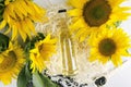 Glass bottle of vegetarian sunflower oil, sunflowers, wooden chips, wooden spoon of seeds on the white table, top view Royalty Free Stock Photo