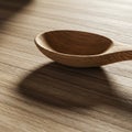 A wooden spoon with a smooth, rounded bowl lies on a wooden surface. The spoon Royalty Free Stock Photo