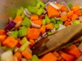 Wooden spoon in freshly chopped vegetables cooking in a pan on the hob Royalty Free Stock Photo