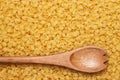 Wooden spoon on uncooked macaroni background