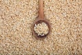 Wooden spoon on unrefined rice background