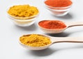 Wooden spoons and bowls with paprika and turmeric powder on white
