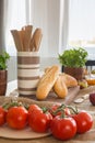 Wooden spoons in container next to baguettes on dining table with tomatoes Royalty Free Stock Photo