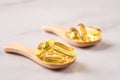 Wooden spoons with dietary supplement omega 3 on marble table background