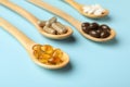 Wooden spoons with different dietary supplements on light blue background Royalty Free Stock Photo