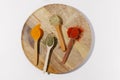 Wooden spoons with filled and scattered spices on a round wooden plate on a white isolated background. Concept of aromatic and Royalty Free Stock Photo