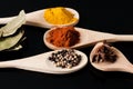 Wooden spoons filled with spices on black background Royalty Free Stock Photo