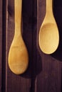 Wooden spoons one shorter than the other hang on a wooden Burgundy wall