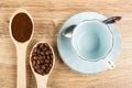 Spoons with coffee beans, ground coffee, blue cup, spoon on saucer on wooden table. Top view Royalty Free Stock Photo