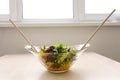 wooden spoons stir salad in a glass plate corn tomatoes cucumbers bulgarian yellow peppers arugula leaves vegetarian