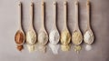 Wooden spoons of various gluten-free flours arranged in a row on a beige background