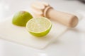Wooden squeezer and lime cut on half on a table on a white plastic cutting board Royalty Free Stock Photo